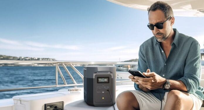 A man charging his phone by the sea