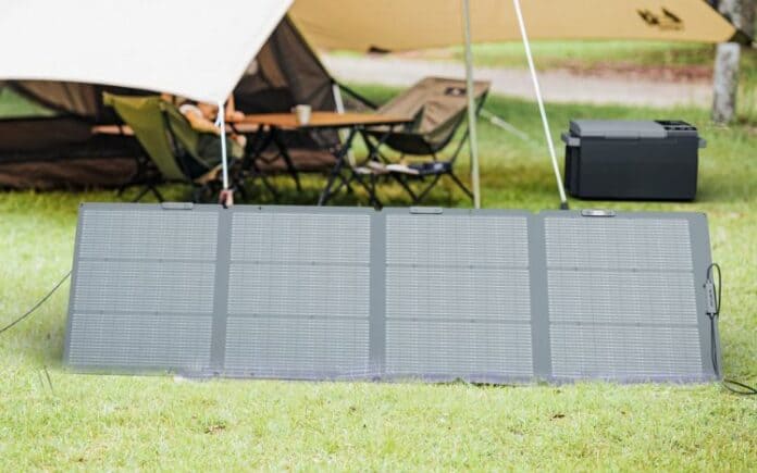 A solar panel next to a tent on a grassy field