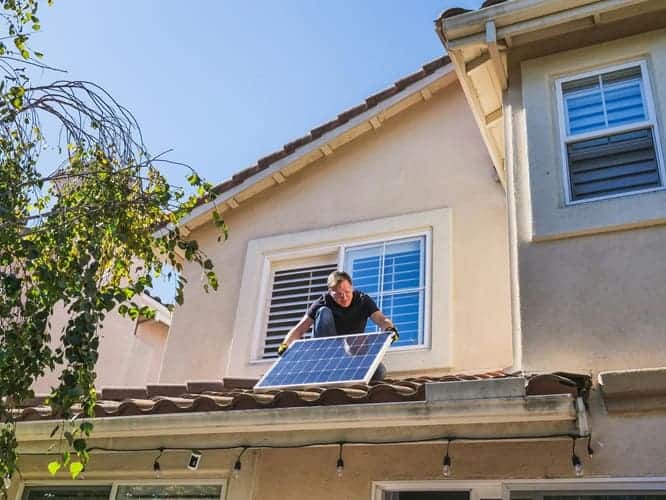 A man installs a solar panel on the roof