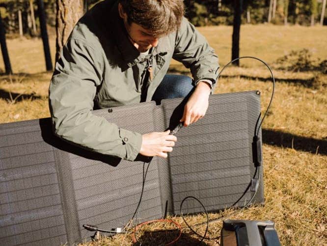 A man setting up a portable solar panel outdoors