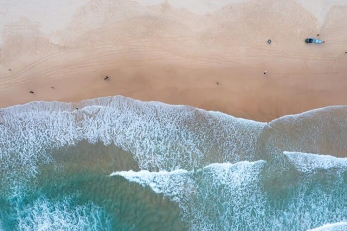 Aerial view of ocean waves crashing onto a sandy beach