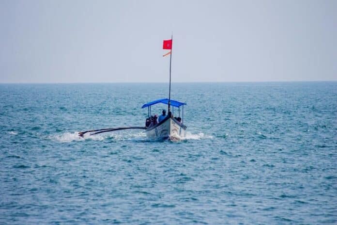 Small fishing boat with a red flag sailing in the sea