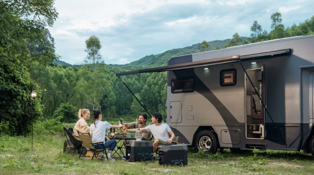 A group of people is picnicking in front of their RV and using EcoFlow's portable power station. 